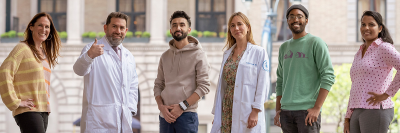 Four people who were successfully treated for rectal cancer in a clinical trial at Memorial Sloan Kettering are seen posing outdoors with the trial’s two principal investigators. 